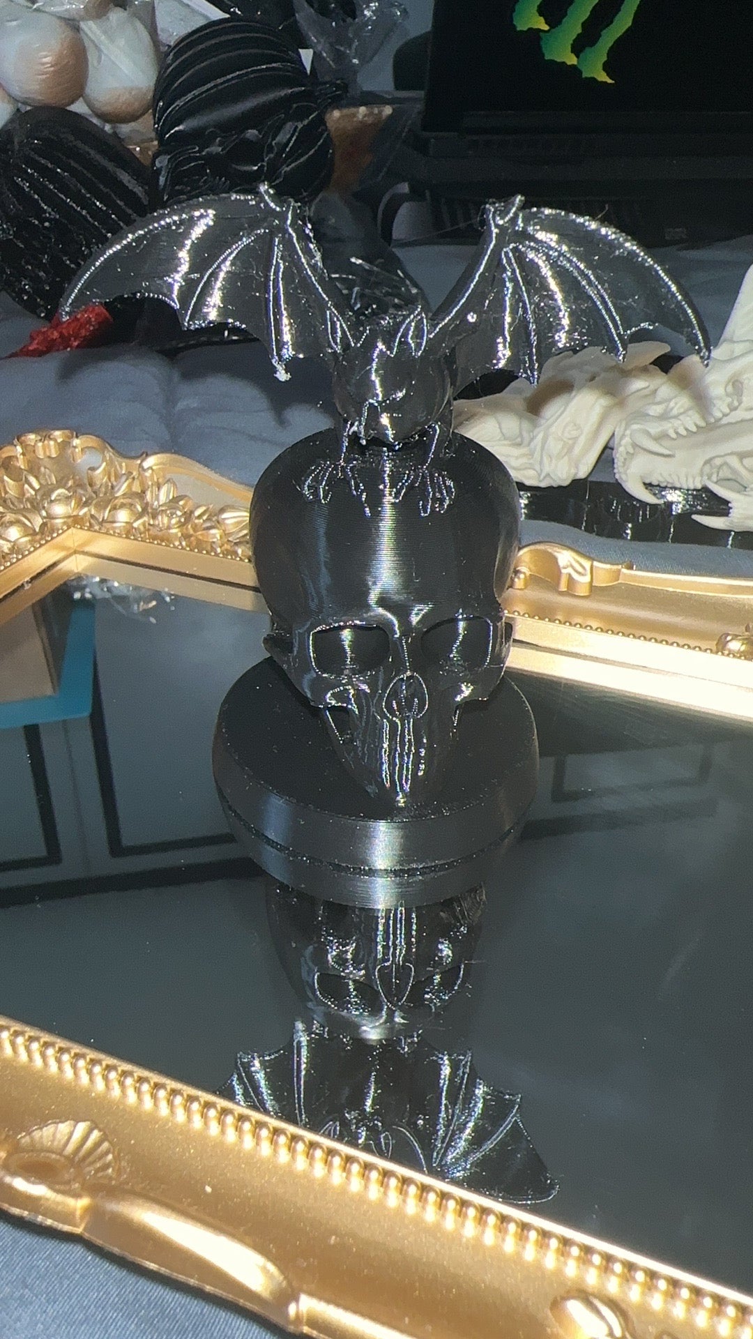 Black 3D printed bat perched on a skull with round display base
