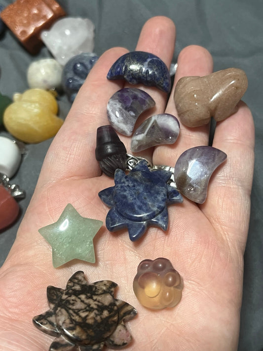 A handful of polished crystal carvings and moons from Hex & Harmony Crystals